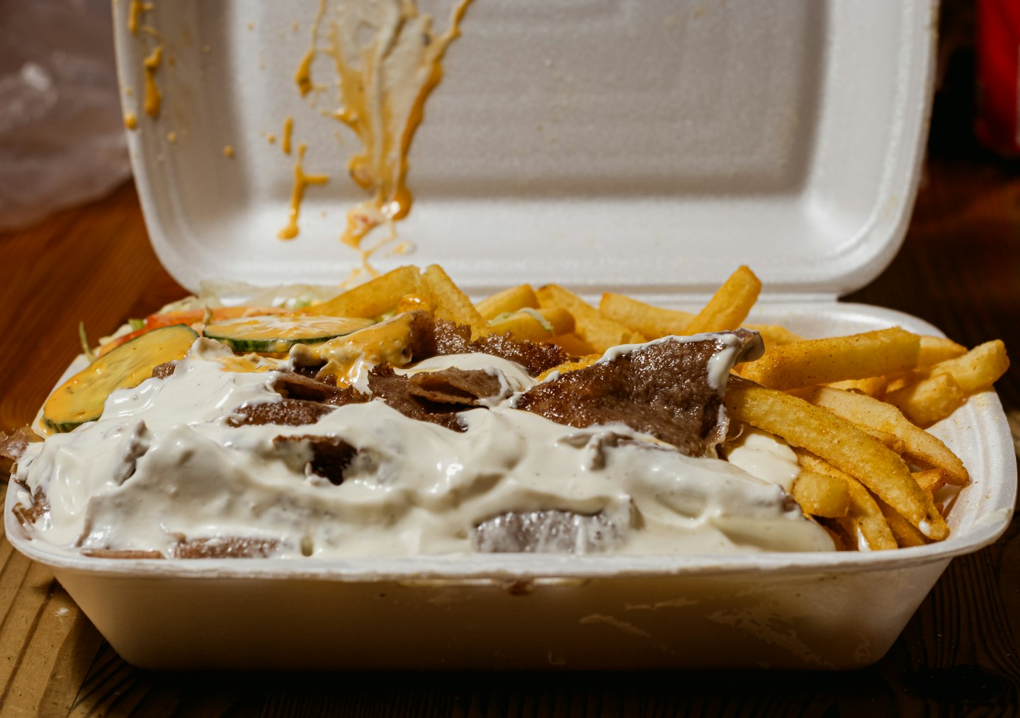 Kontajner na doner kebab s hranolkami, uhorkou, šalátom a omáčkami.